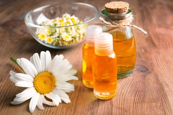 Essential oil and chamomile flowers — Stock Photo, Image