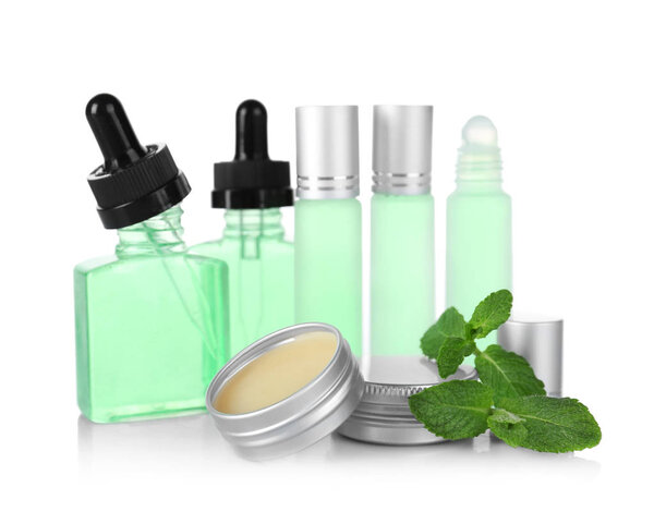 Бутылки, контейнеры с духами и листья мяты на белом фоне
