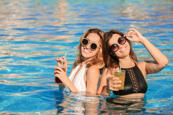 Duas mulheres com cocktails na piscina — Fotografia de Stock