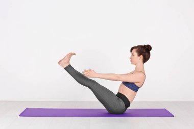 Beyaz arka planda yoga yapan genç bir kadın.