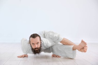 Genç adam pratik Yoga ışık duvar arka plan üzerinde