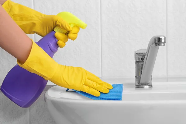 Frau putzt Waschbecken mit Schwamm — Stockfoto