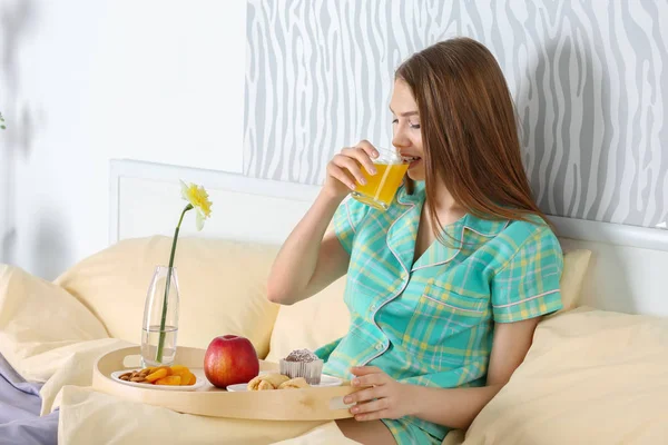 Ung vacker kvinna äter frukost i sängen — Stockfoto