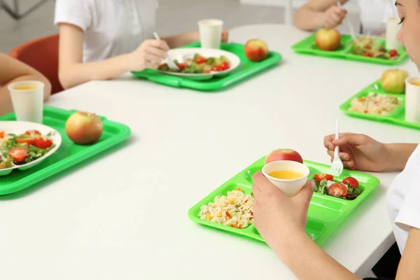 Bambini seduti a tavola nella mensa della scuola mentre pranzano — Foto Stock