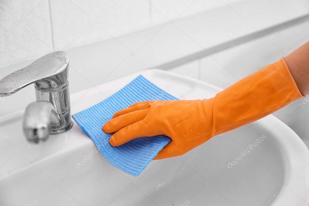 hand with sponge cloth cleaning sink