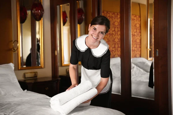 Kamermeisje zet schone handdoeken op bed in hotelkamer — Stockfoto