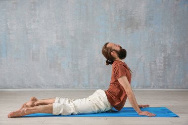 Genç adam gri duvar arka plan üzerinde Yoga uygulamak