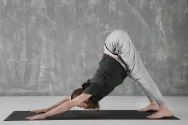 Genç adam gri duvar arka plan üzerinde Yoga uygulamak