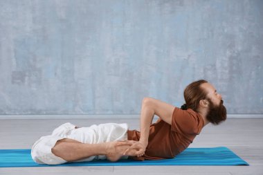 Genç adam gri duvar arka plan üzerinde Yoga uygulamak
