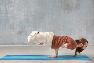 Genç adam gri duvar arka plan üzerinde Yoga uygulamak
