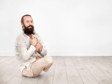 Genç adam pratik Yoga ışık duvar arka plan üzerinde