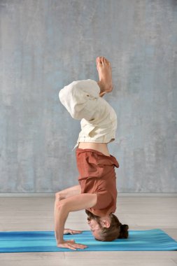 Genç adam gri duvar arka plan üzerinde Yoga uygulamak