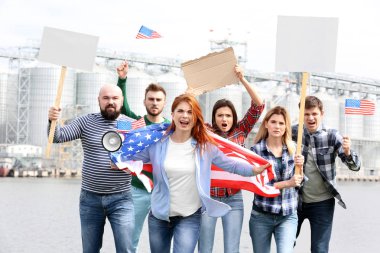 Amerikan bayrağı ve Fabrika arka plan üzerinde gençlerle protesto grubu