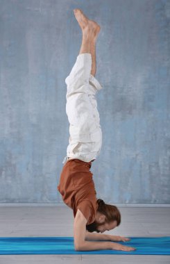 Genç adam gri duvar arka plan üzerinde Yoga uygulamak