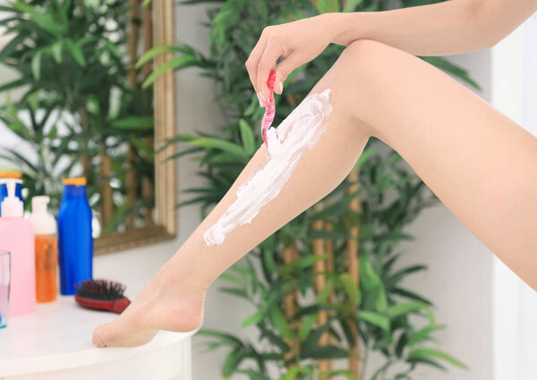 Young woman shaving leg 