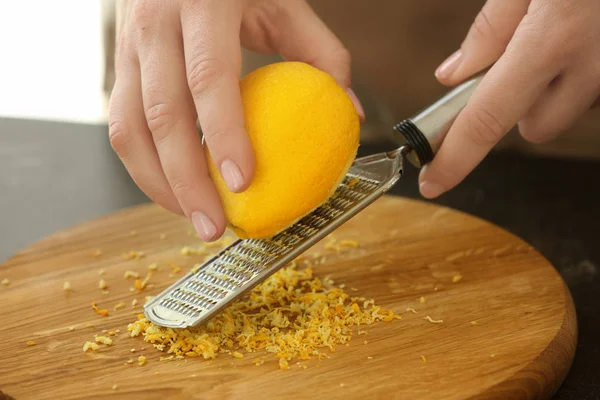 Ralladura mujer ralladura de limón en la mesa de la cocina — Foto de Stock