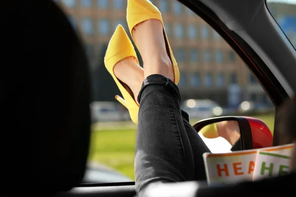 Junge Frau mit schlanken Beinen in High Heels entspannt im Auto — Stockfoto