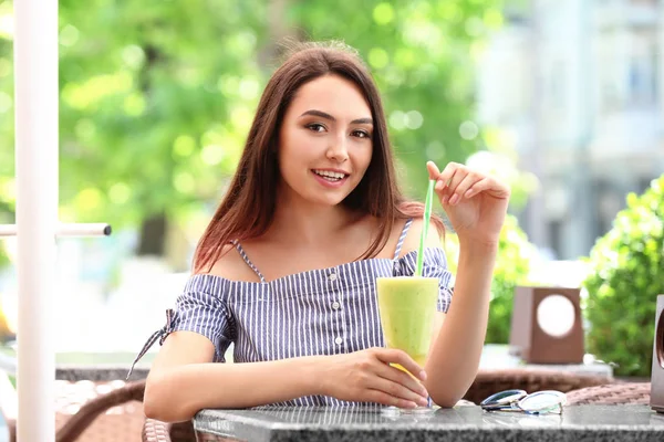 Jolie jeune femme qui boit du smoothie au café — Photo
