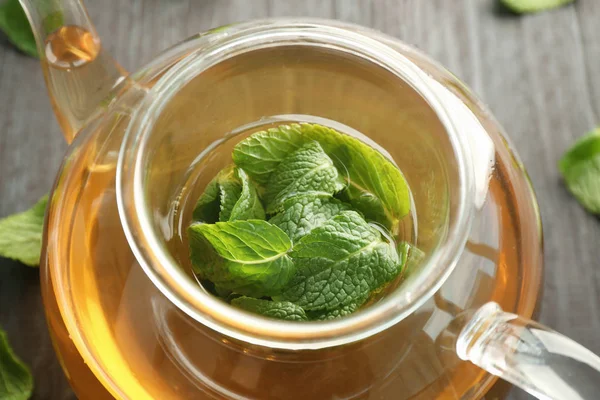 Tekanna aromatiska te med citronmeliss på träbord — Stockfoto