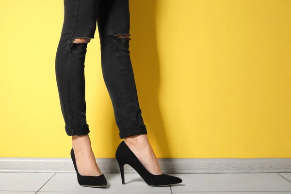 Junge Frau mit schlanken Beinen in High Heels nahe der Farbwand — Stockfoto