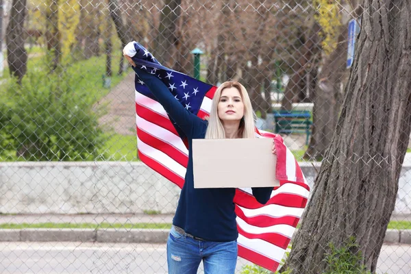 Protesting young woman holding piece of cardboard with space for text and American flag on street — Stock Photo, Image