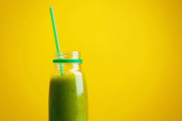 Flaska med fräsch frisk grön smoothie på färgbakgrund — Stockfoto