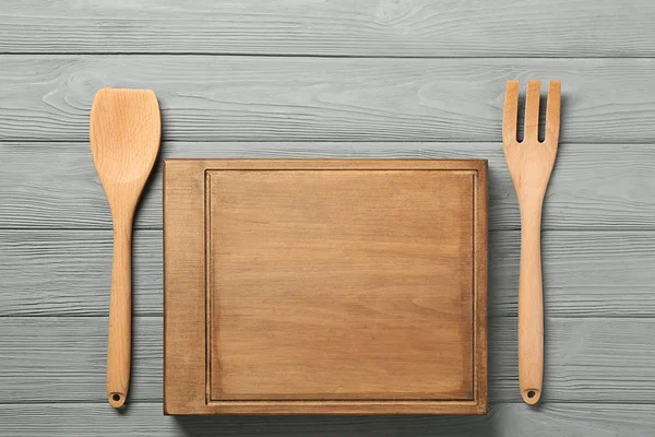 Board and utensils on wooden background — Stock Photo, Image