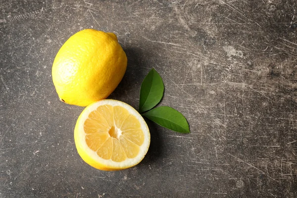 Deliciosos citrinos fatiados e folhas verdes sobre fundo cinza — Fotografia de Stock