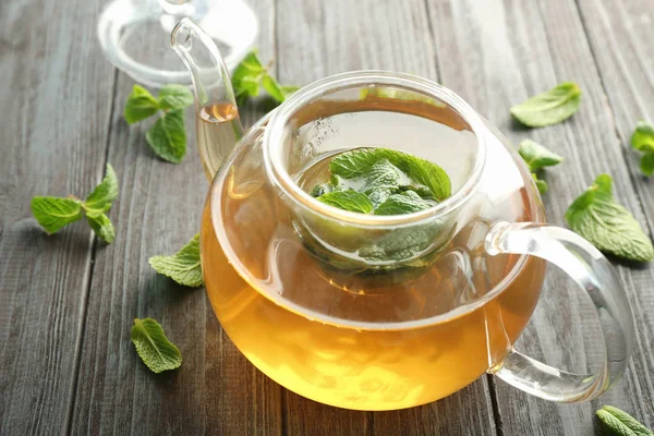 Tekanna aromatiska te med citronmeliss på träbord — Stockfoto
