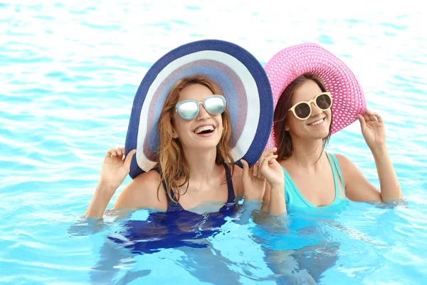 Jovens mulheres bonitas relaxando na piscina azul — Fotografia de Stock