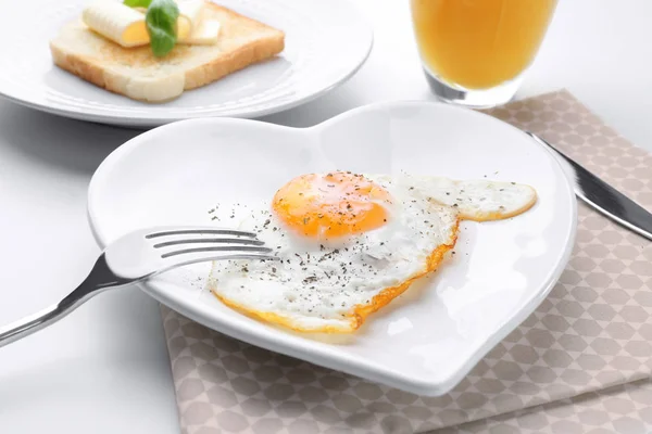 Cutlery and plate with over hard fried egg on light table — Stock Photo, Image