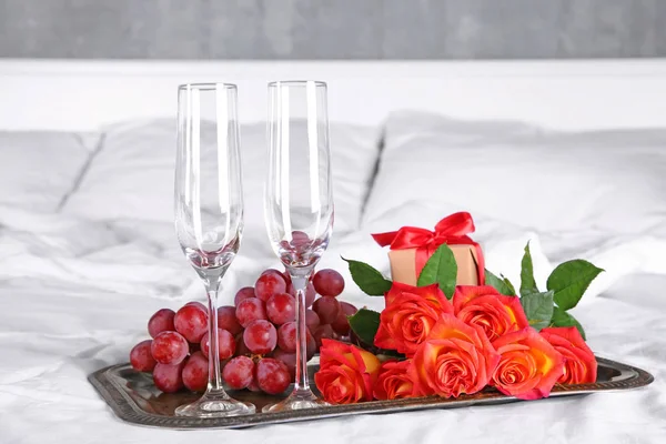 Zásobník s prázdné sklenky na sekt, hroznů a růže pro romantickou večeři na posteli. Svatební koncept — Stock fotografie