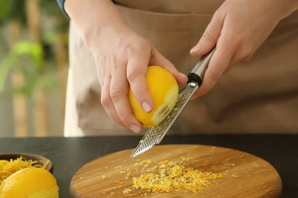 Жінка натирає цедру лимона на кухонному столі — стокове фото