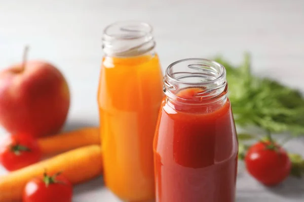 Deliciosos jugos de zanahoria y tomate en botellas sobre mesa, primer plano — Foto de Stock