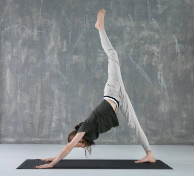 Genç adam gri duvar arka plan üzerinde Yoga uygulamak