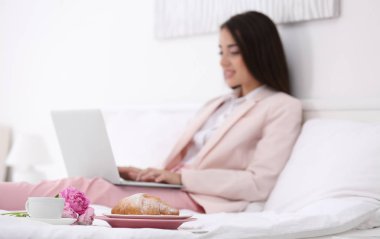 Güzel genç kadın yatakta otel odasında bir dizüstü bilgisayar kullanarak