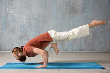 Genç adam gri duvar arka plan üzerinde Yoga uygulamak