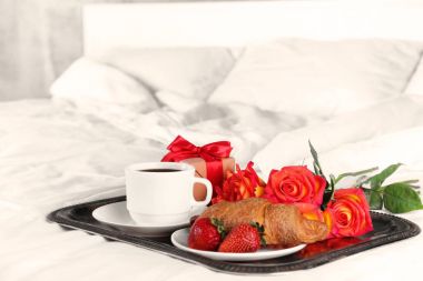 Romantik kahvaltı kahve, çilek ve kruvasan tepsi yatak odasında. Balayı konsepti