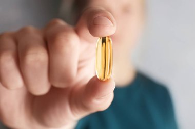 Balık yağı hapı bulanık arka plan üzerinde kadının elinde