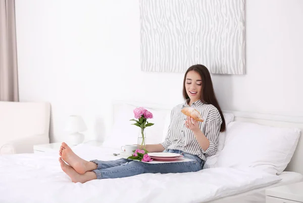 Hermosa mujer joven desayunando en la habitación de hotel en la cama — Foto de Stock