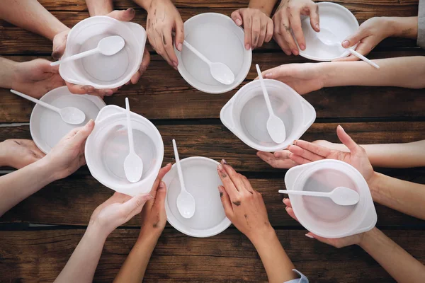 Hands of people with empty bowls at wooden table. Poverty concept — Stock Photo, Image