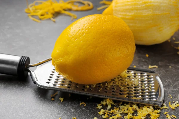 Grater with lemon and zest on table, closeup — Stock Photo, Image