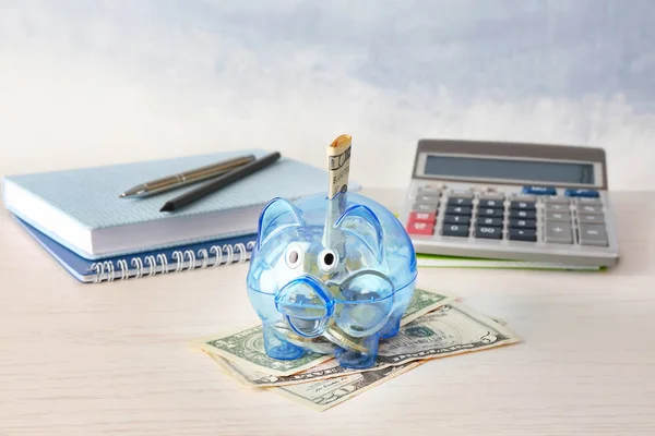 Sparschwein mit Geld, Schreibwaren und Taschenrechner auf dem Tisch. Sparkonzept — Stockfoto