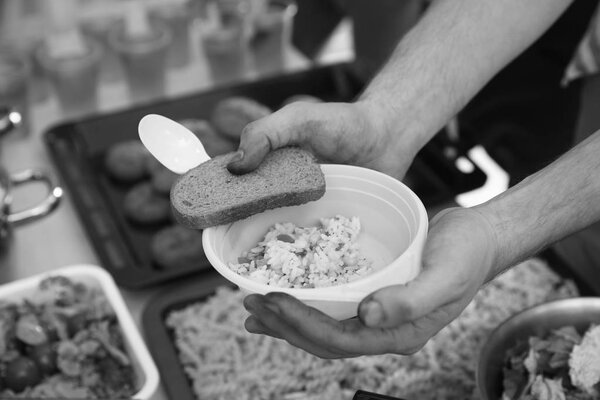 Hands of poor man holding bowl with rice and bread. Poverty concept