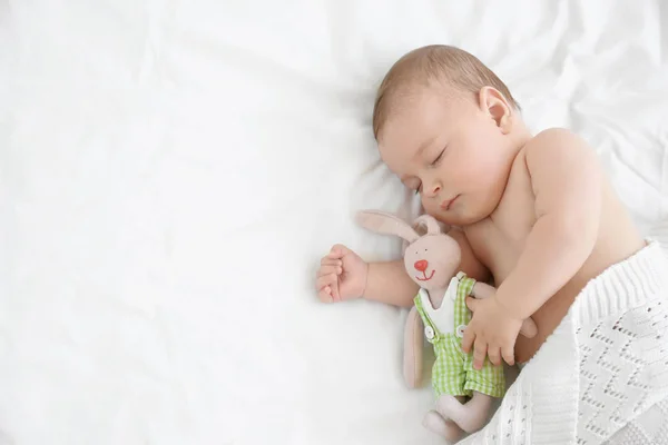 Χαριτωμένο μικρό μωρό με το παιχνίδι στον ύπνο στο κρεβάτι στο σπίτι — Φωτογραφία Αρχείου