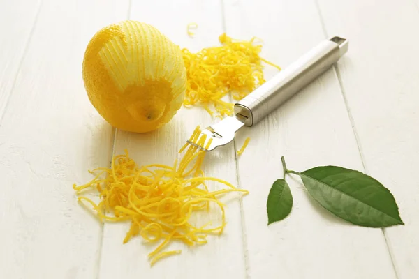 Citron pelé frais, outil spécial et zeste sur table en bois — Photo