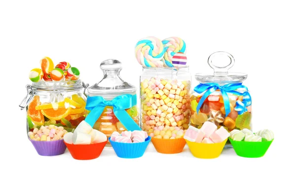 Doces diferentes em frascos de vidro e formas em fundo branco — Fotografia de Stock