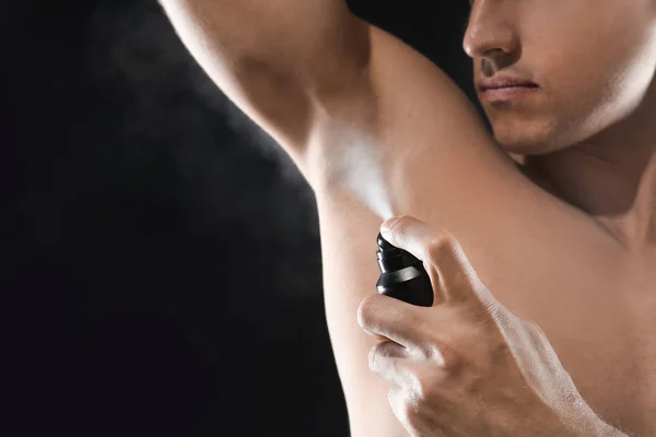 Pohledný mladý muž s deodorant na tmavém pozadí — Stock fotografie