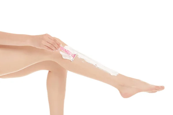 Junge Frau rasiert Bein auf weißem Hintergrund — Stockfoto