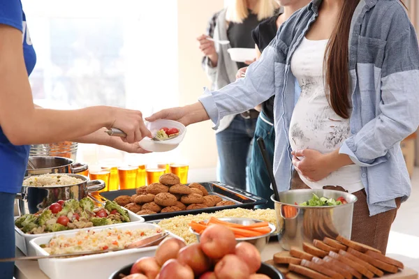 Pregnant woman receiving food from volunteer. Poverty concept — Stock Photo, Image